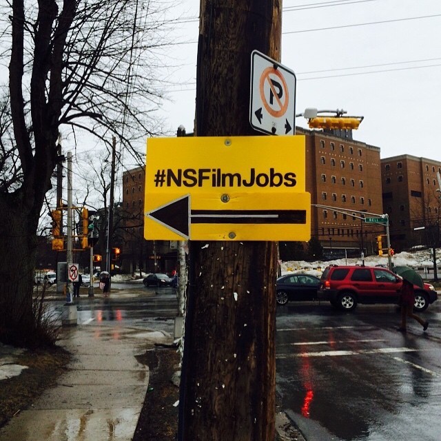 A sign with #NSFilmJobs attached to a telephone pole with an arrow pointing to the left.